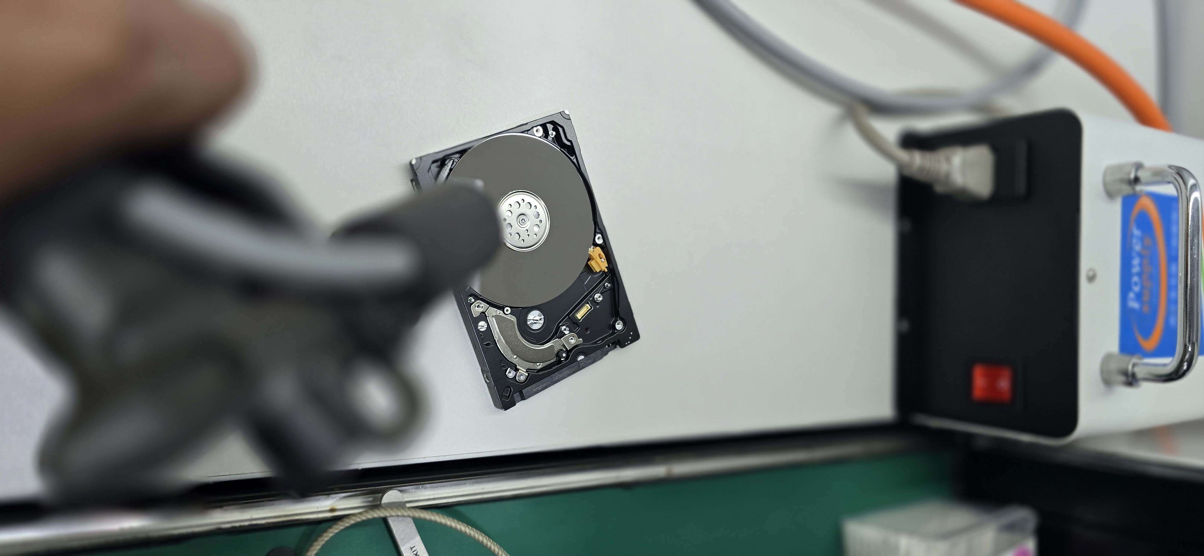 Recovery.uz иш столида қопқоғи олинган HDD; олдинда ионлаш пистолети, орқада қувват блоки